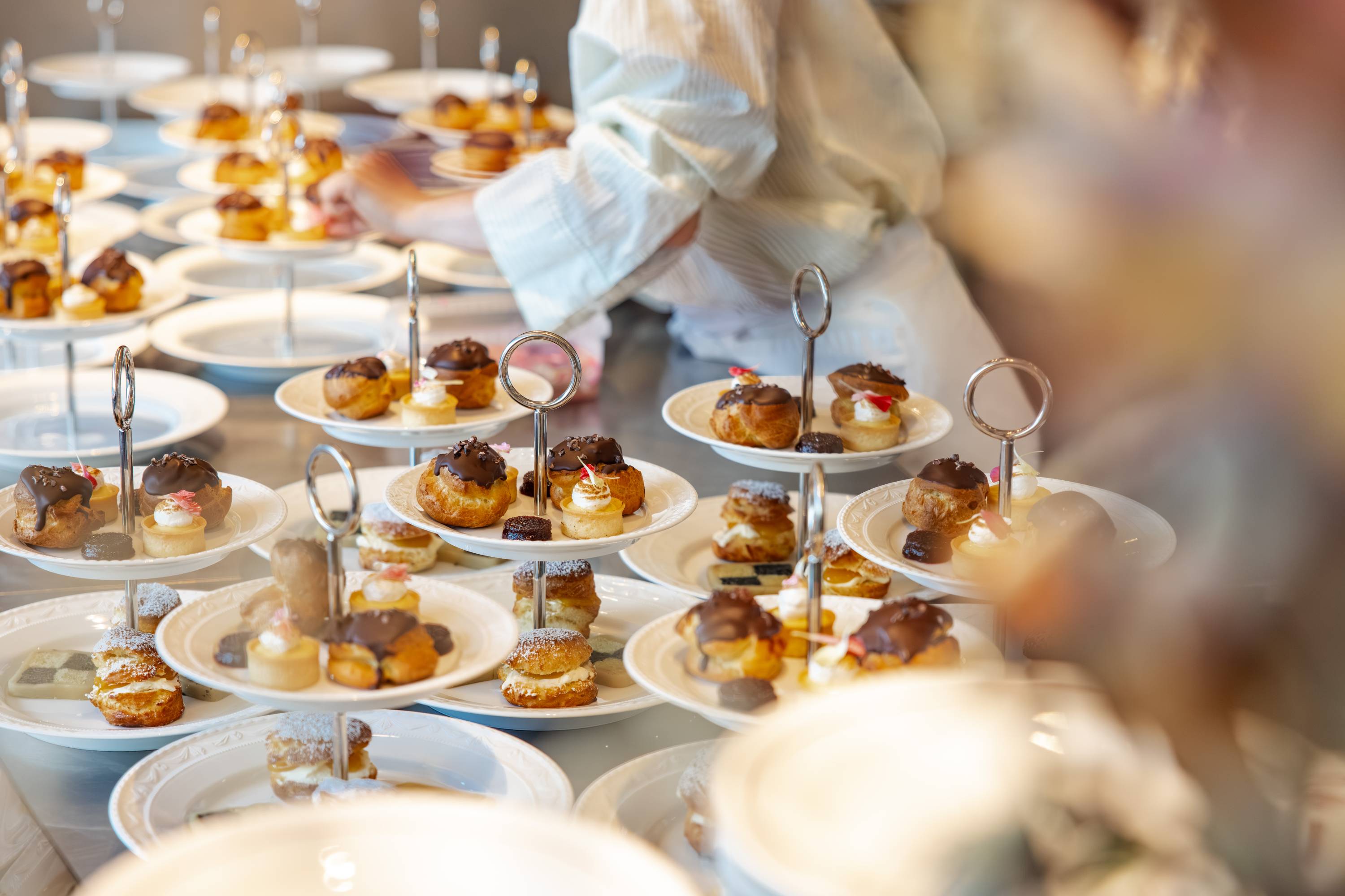 Mehrstöckiges Serviertablett mit Schokoladen-Cremebällchen und verzierten Kuchen auf weißen Tellern