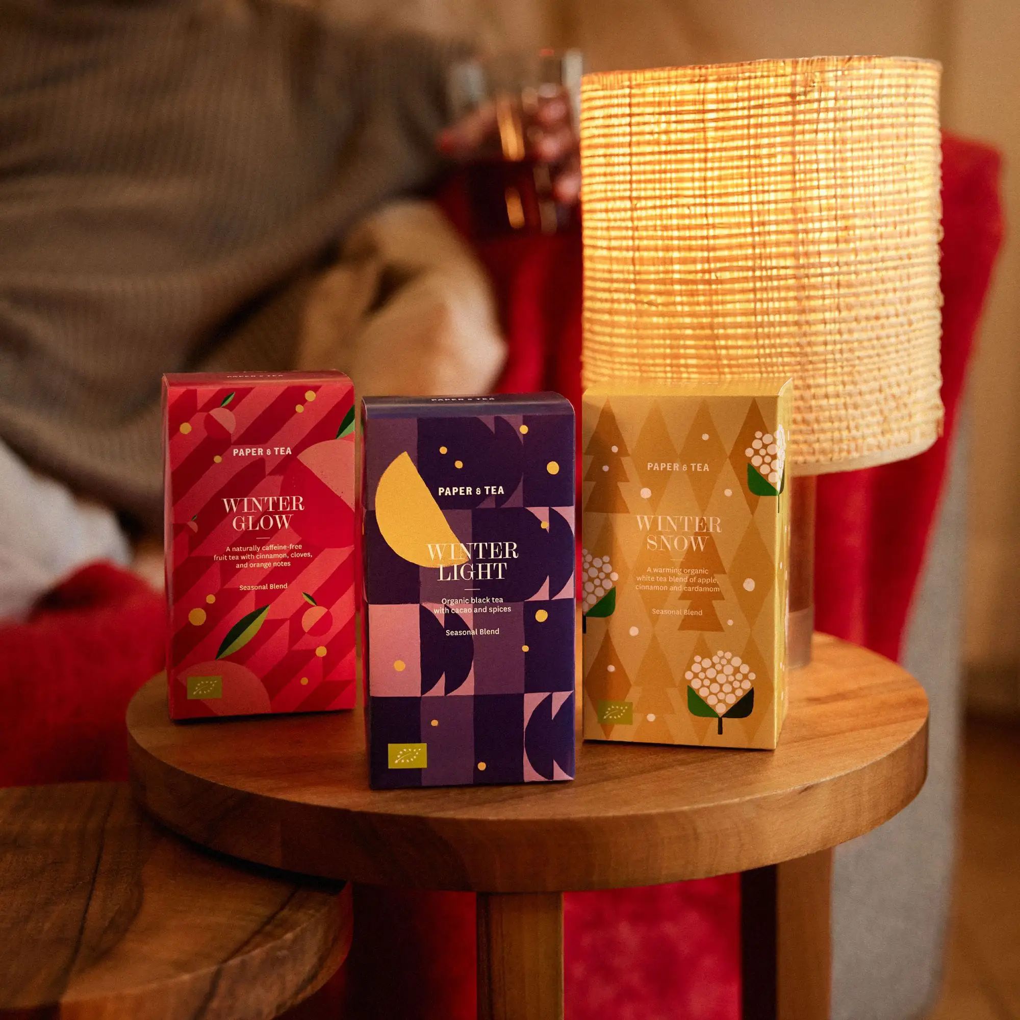 Drei PAPER & TEA Wintertee-Boxen mit WINTER GLOW, WINTER LIGHT und WINTER SNOW auf Holztisch.