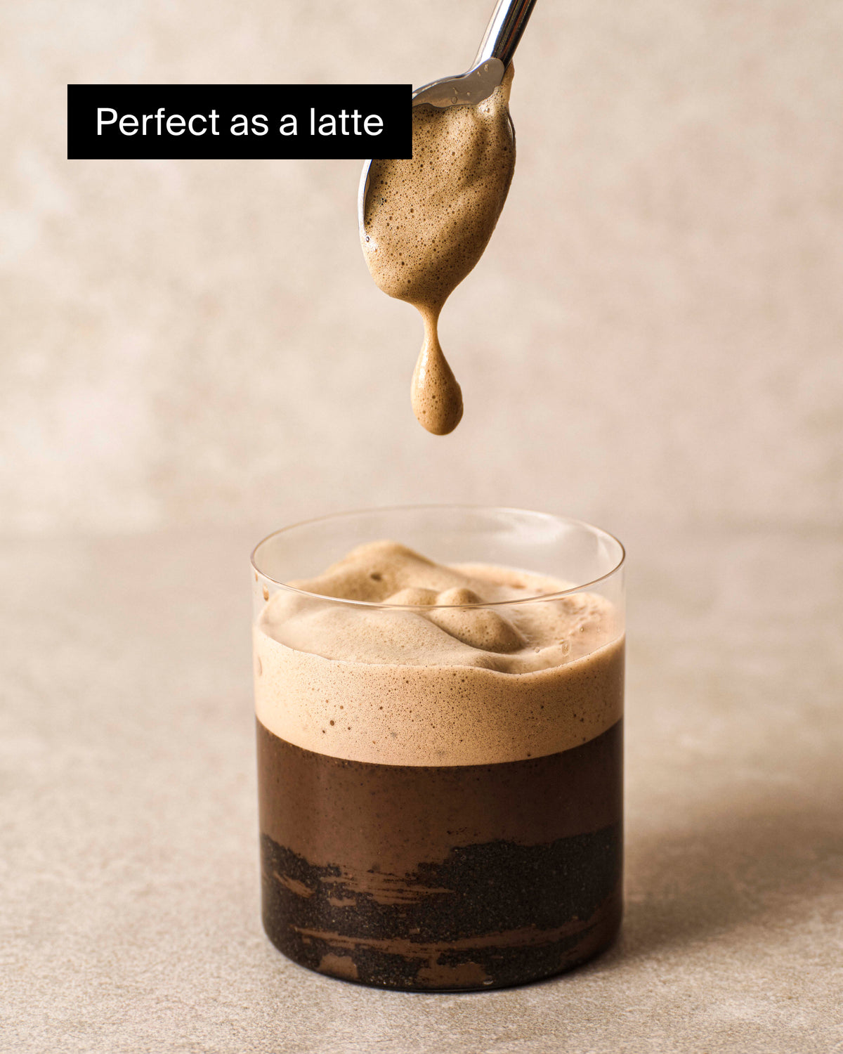 Latte im klaren Glas mit cremigem Schaum auf neutralem Untergrund