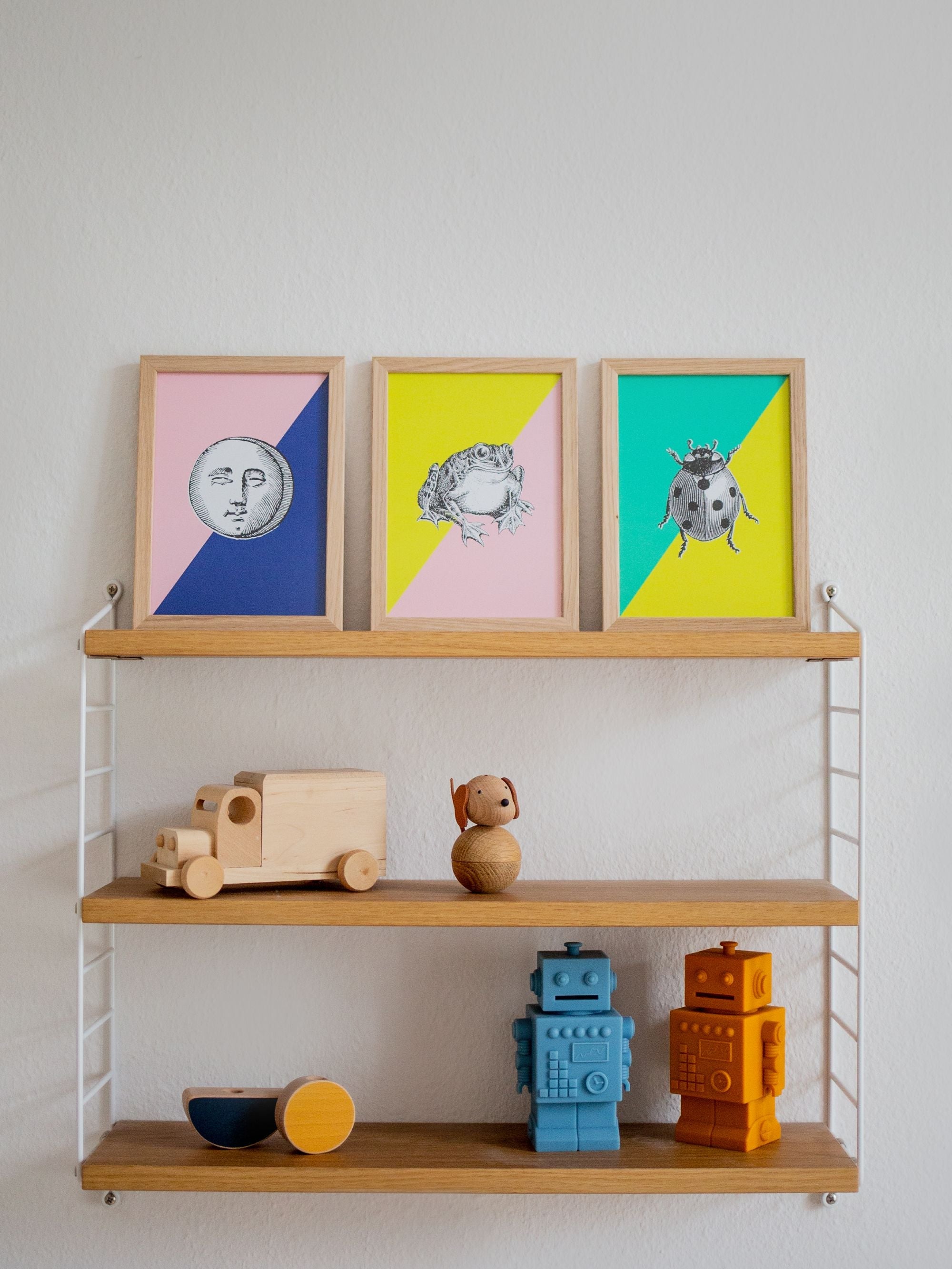 Dreistufiges Holzregal mit bunten Tier- und Mondbildern sowie Holzspielzeugen wie Lastwagen und Robotern.