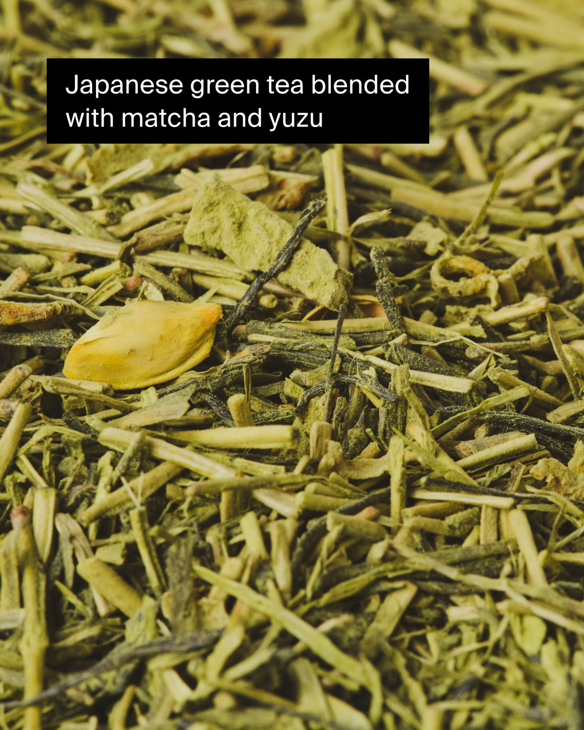Nahaufnahme von japanischem Grüntee mit Matcha-Pulver und Yuzu-Stücken, grüne und gelbliche Teemischung.