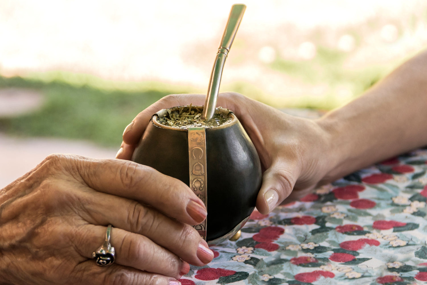 Zwei Hände, die sich Kalebasse reichen zum Mate-Trinken