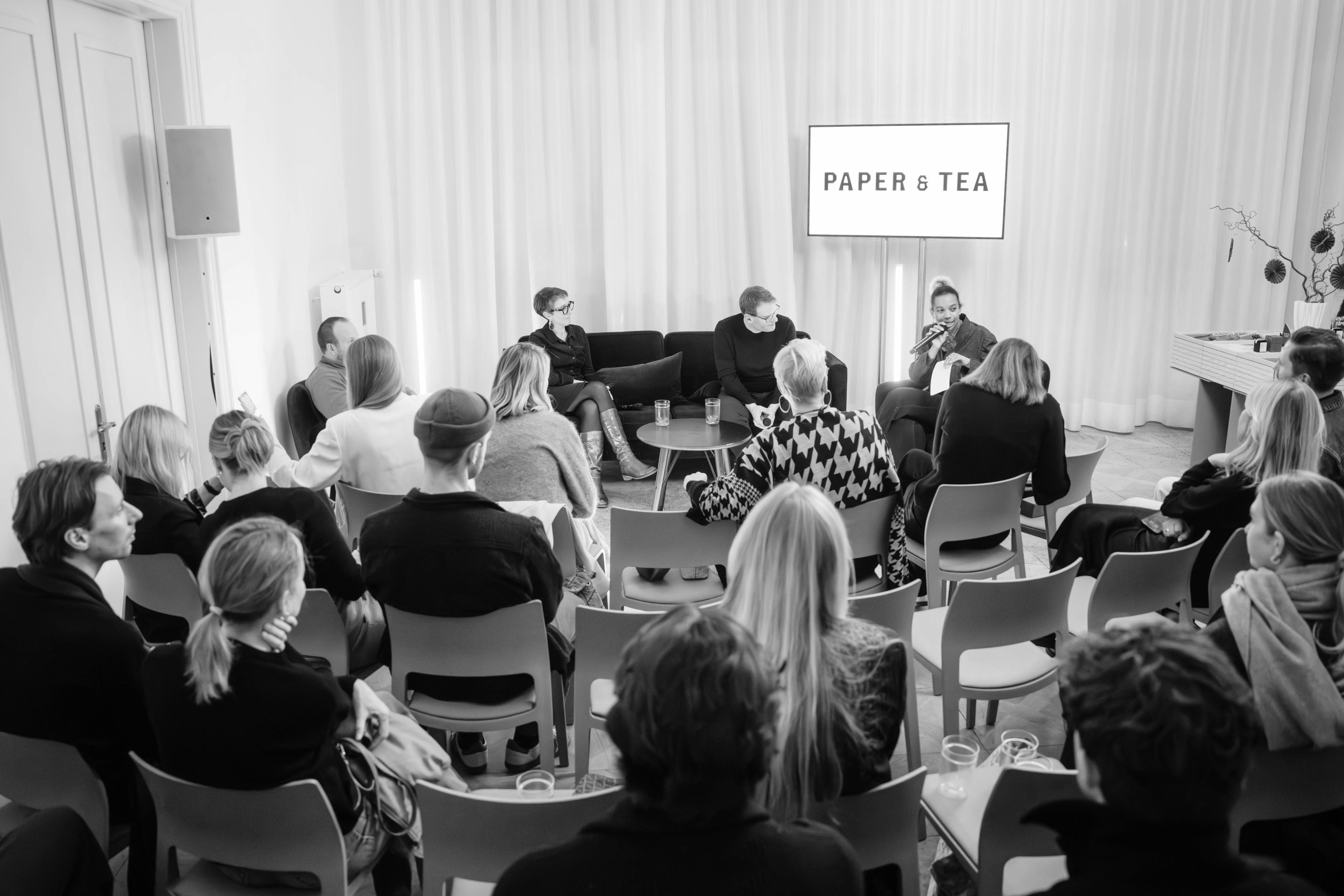 Podiumsdiskussion mit drei Panelisten vor P&T-Logo und aufmerksamem Publikum