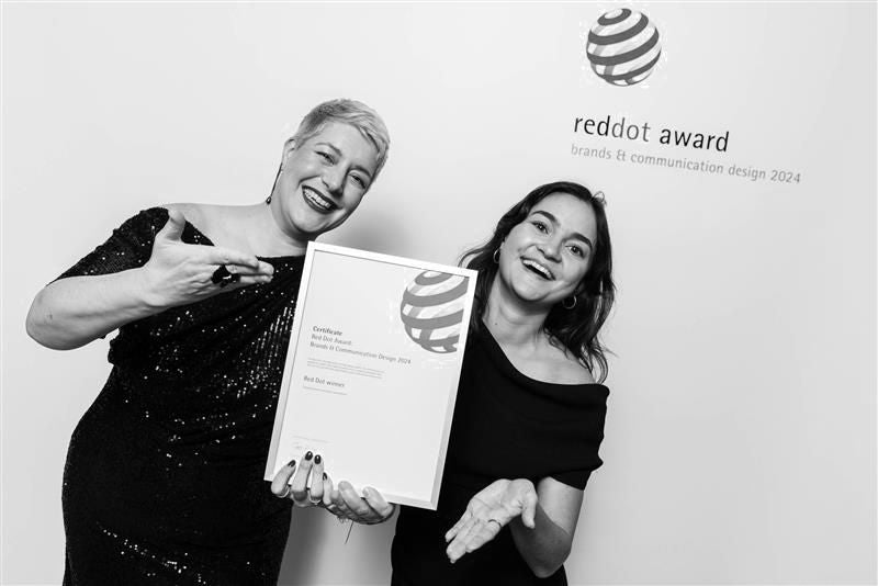 Zwei Frauen feiern mit einem Red Dot Award Zertifikat