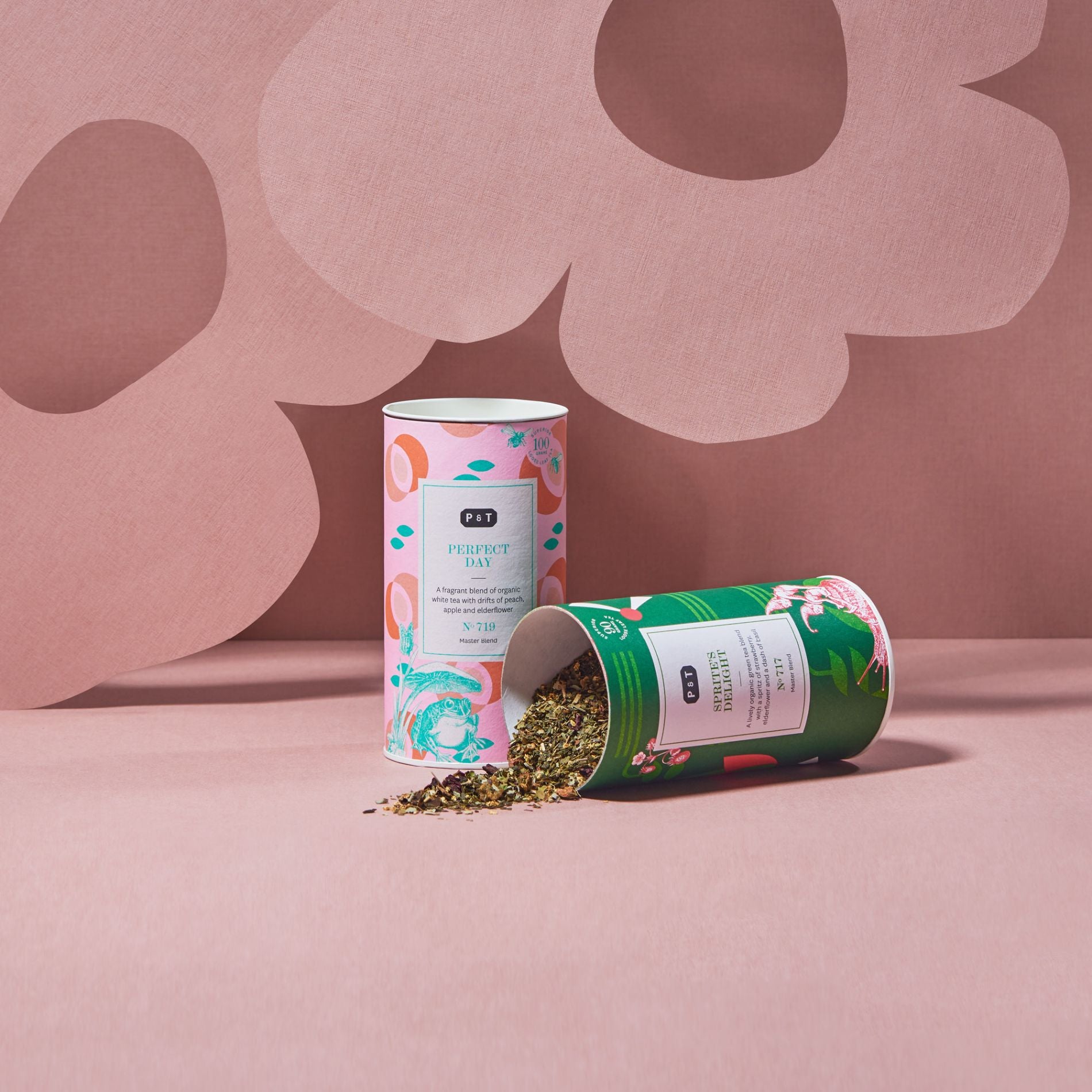 Zwei P & T Teedosen auf rosa floralem Hintergrund: Weißer Tee mit Pfirsich und grüner Tee mit Blüten.