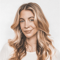 Porträt unserer PR Christina Meyer mit langen, blonden Haaren und sanftem Lächeln vor hellem Hintergrund.