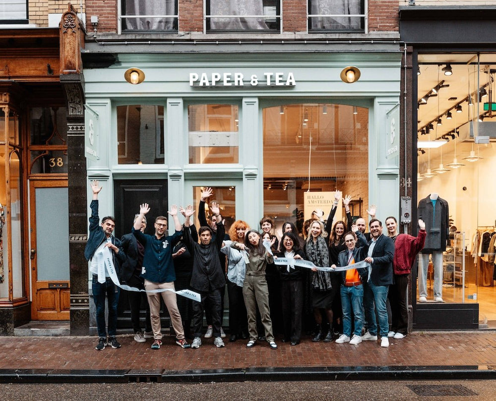 Gruppe vor mintgrüner PAPER & TEA Ladentür mit gelben Lichtern und Hausnummer 38